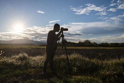 Man photographing on field against sky