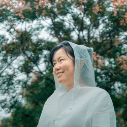 Portrait of smiling woman standing against trees