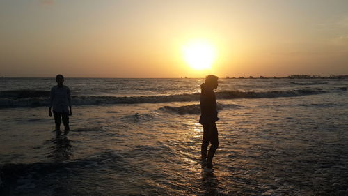 Silhouette of people on beach at sunset