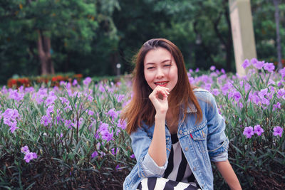 Woman sitting by purple flowers at park