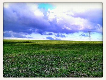 Scenic view of grassy field against cloudy sky