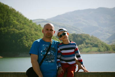Portrait of man with son against lake and mountains