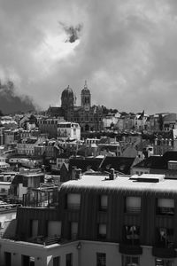 Buildings in city against cloudy sky