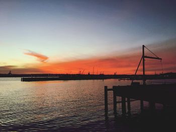 Silhouette pier on calm sea at sunset