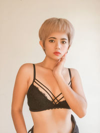 Portrait of young woman standing against white background