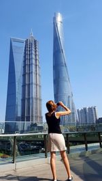 Rear view of woman standing against modern cityscape