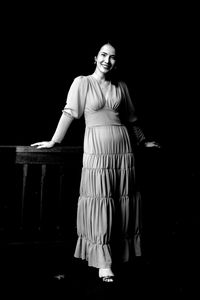 Portrait of woman standing against black background