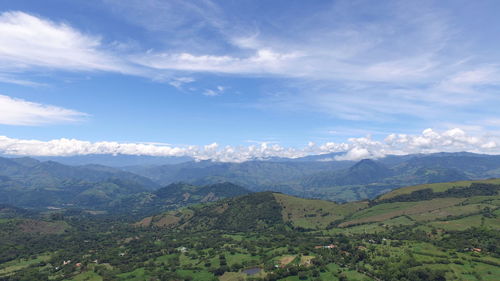 Aerial view of green valley against cloudy sky