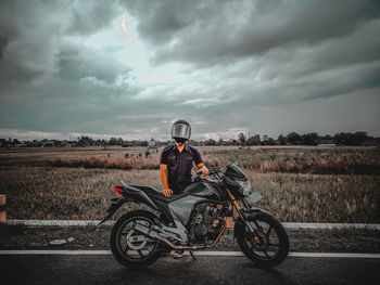 Man riding bicycle on road against sky