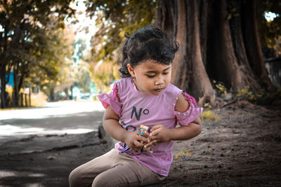 Full length of cute girl sitting on land