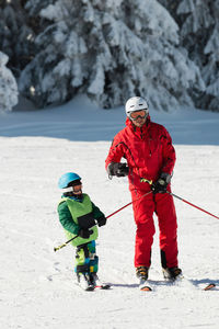 Full length of father and son skiing on snow during winter