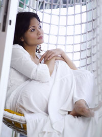 Woman sitting in swing chair at home