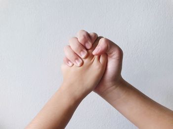 Close-up of woman hand against white wall