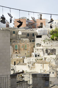 Low angle view of shoes hanging from cable against cityscape