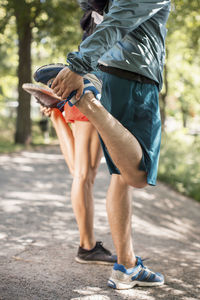 Low section of couple doing stretching exercises together on street