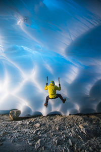 Rear view of man ice climbing in glacier cave.