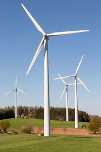 Wind turbine on field against clear sky