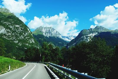 The roadway with mountain landscape, blue sky and white clouds over alpine peaks, brenta dolomites.