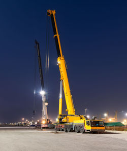 Low angle view of crane against clear sky at night