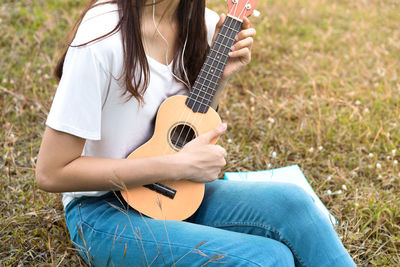 Midsection of woman playing ukulele on grass