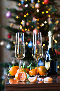 Two glasses of champagne and a tangerine on the background of a festive christmas tree.