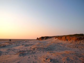 Scenic view of beach against clear sky during sunset