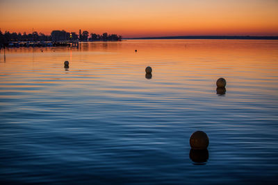 Silhouette buoy in sea during sunset