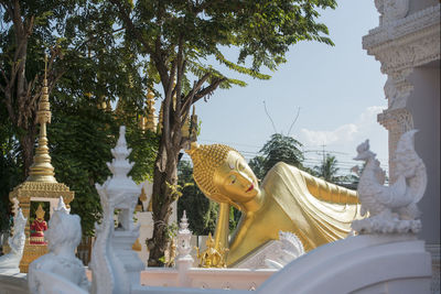 Statue amidst trees and buildings against sky