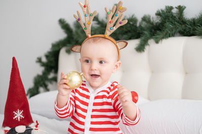 Cute girl playing with bauble sitting at home