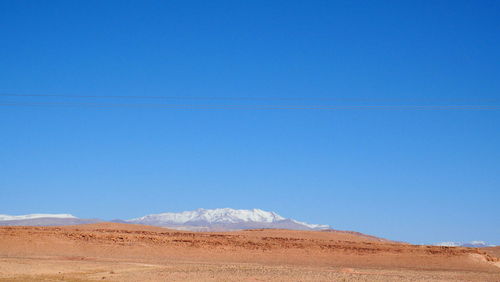 Scenic view of arid landscape against clear blue sky