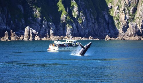 Boat sailing on sea against rock formation