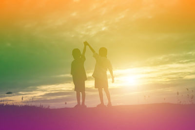 Silhouette people standing on land against sky during sunset