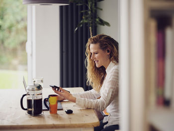 Smiling businesswoman using mobile phone while working at home