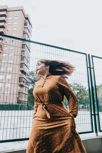 Young woman standing against building