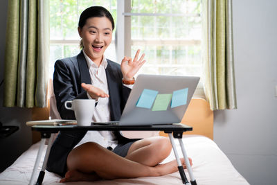 Young woman using mobile phone while sitting on table