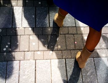 Low section of woman standing on cobblestoned footpath 