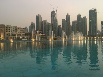 Sea by modern buildings against clear sky in city
