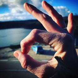 Close-up of human hand against sky