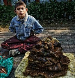 Portrait of teenage boy selling honey on street