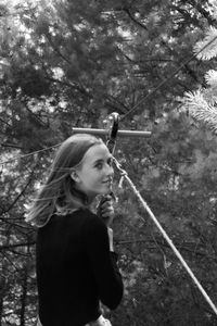 Young woman standing by tree in forest