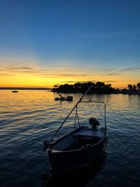 Silhouette boats moored in lake against sky during sunset