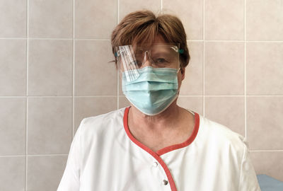 Woman scientist wearing face mask, protective gloves and medical medical gown working 