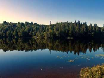 Scenic view of lake by trees against sky