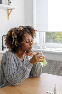 Side view of young woman sitting on table