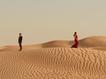 Man on sand dune in desert against clear sky