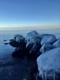 Rocks on sea shore against clear sky