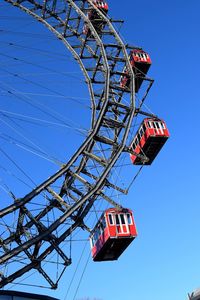 Low angle view of ferris wheel against clear blue sky