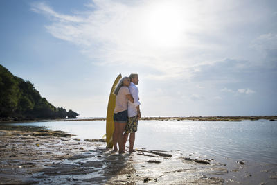 Affectionate senior couple with surfboards at beach