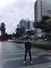 Full length of man standing on street against buildings in city