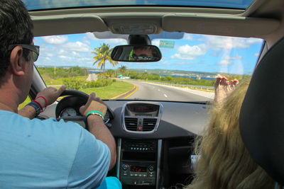 Rear view of people traveling in car against sky